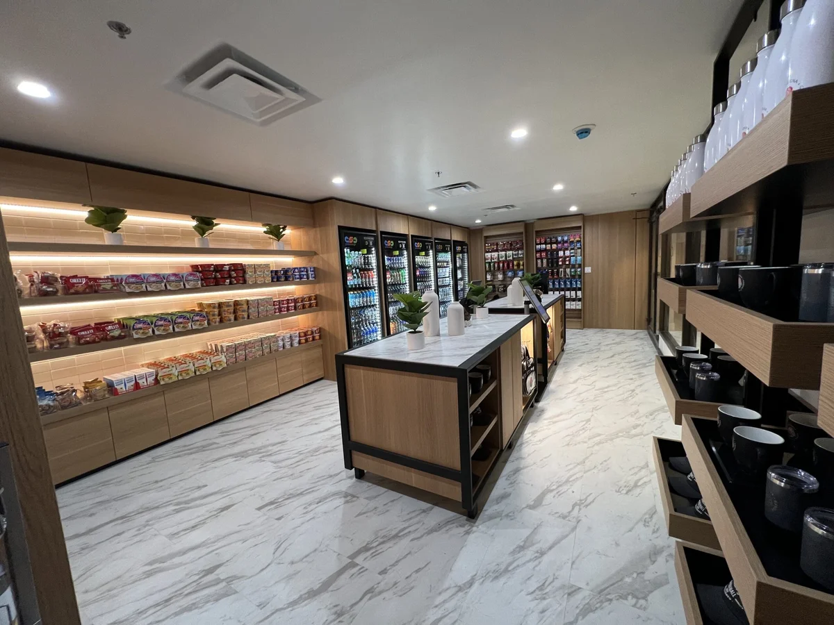 Hotel market with snack shelves, a central display counter and seating along the wall.